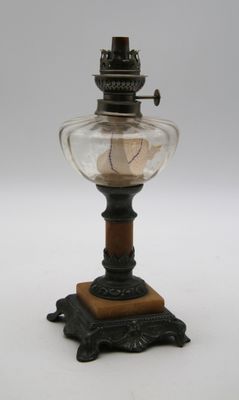une lampe à huile à l'ancienne, dotée d'un abat-jour en verre et posée sur un socle en bois