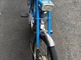 a small blue bike parked on the side of the road