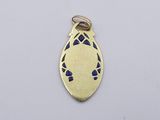 a close up of a gold plated pendant on a white surface