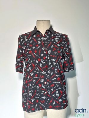 Le t-shirt est noir, avec des flèches rouges et blanches dessus.