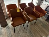 quatre fauteuils en cuir marron, avec une étiquette de prix, placés devant une vitrine