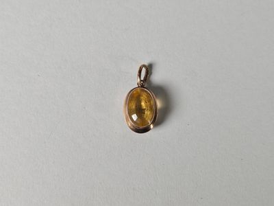 un petit pendentif orné d'une pierre jaune sur un fond blanc