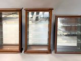 three wooden display cases with glass doors on a white surface