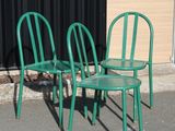 three green chairs sitting next to each other in front of a building