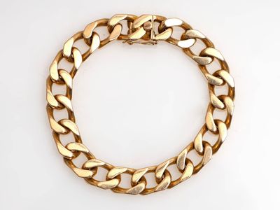 gros plan d'un bracelet en chaîne en or sur une surface blanche