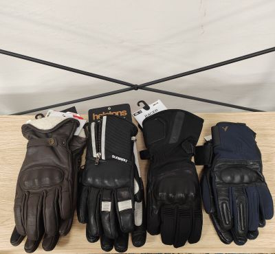 cinq paires de gants en cuir sont alignées sur une étagère en bois