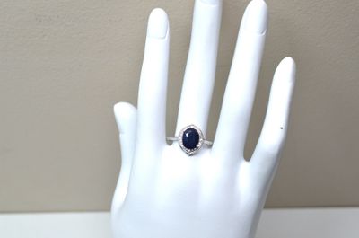 une main sur laquelle est passée une bague sertie d'une pierre bleue