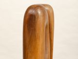 a wooden sculpture on a white pedestal on a white surface