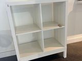 a white bookcase with four shelves in the corner of the room