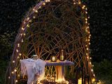 a gazebo with lights and a table in the grass