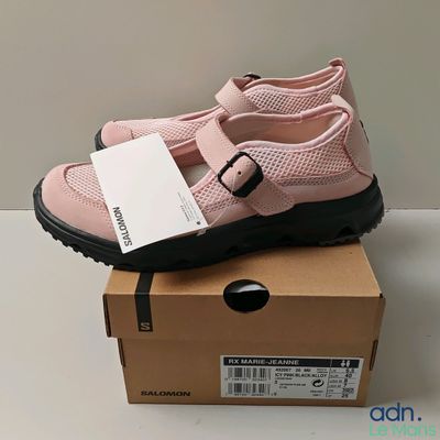des chaussures roses à semelles noires posées sur une boîte, sur une surface blanche