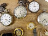 many different types of pocket watches on a wooden table