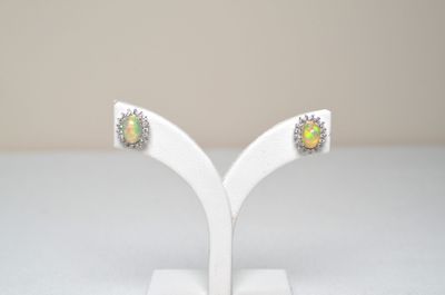 a pair of oplite and diamond earrings on a white stand