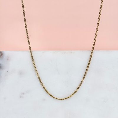 un collier à chaîne en or sur fond rose