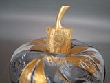 a glass pumpkin with a gold top sitting on a table
