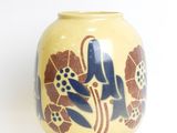 a yellow vase with blue flowers on it on a white surface