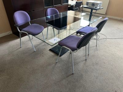 une table en verre entourée de chaises violettes au milieu de la pièce