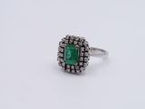 an emerald and diamond ring on a white surface