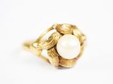 gros plan d'une bague en or avec une perle au centre