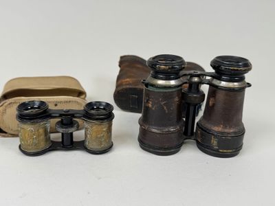 two old binoculars are sitting next to each other on a white surface