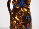 a gold pitcher with a blue design on it