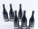 six bottles of wine are lined up in a row on a white surface