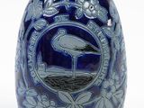 a blue vase with a bird on it on a white background