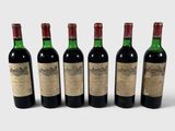 six bouteilles de vin sont alignées sur une surface blanche