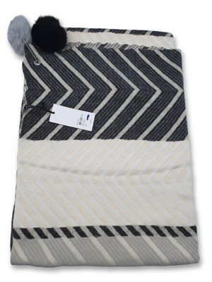 the black and white blanket has a pom pom on it