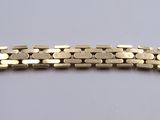 a close up of a gold bracelet on a white surface