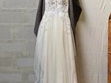 a wedding dress hanging on a hanger next to a brick wall