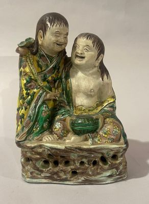 deux figurines représentant un garçon et une fille assis sur un rocher