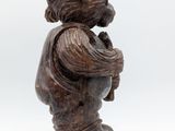 an old wooden statue of a boy with a hat on his head