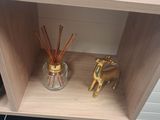 a wooden shelf with a glass vase and a gold horse figurine on top of it