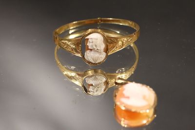 une image représentant une bague en or ornée du portrait d'un homme et d'une pierre orange