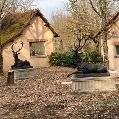 two statues of a deer and a deer laying on the ground