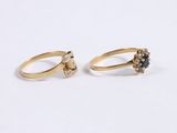 two gold rings with black and white diamonds on a white surface