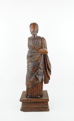 une vieille statue représentant un homme tenant un sac, posée sur un socle en bois