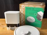 une photo représentant un Roomba et une boîte posés sur une table en bois