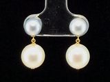 a close up of a pair of pearl earrings on a black background