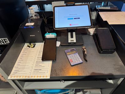 a desk with a laptop, cell phone, and a calculator on it