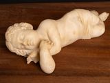 a small statue of a baby laying on a wooden table