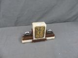 a small clock sitting on top of a wooden stand
