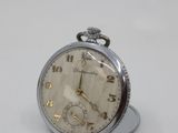 a silver pocket watch sitting on top of a white table