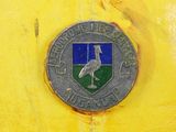 a yellow fire hydrant with a metal emblem on it