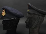 pair of military hats on mannequin heads against a black background