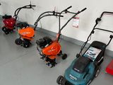 many lawn mowers lined up in a row on the floor