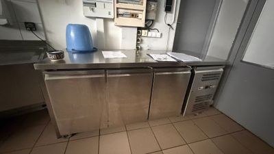 plan de travail en acier inoxydable dans une cuisine professionnelle équipée d'un distributeur d'eau bleu
