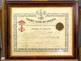 un vieux certificat encadré, accompagné d'une médaille, posé sur une chaise en bois