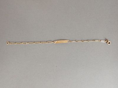 gros plan d'un bracelet en or sur une surface grise